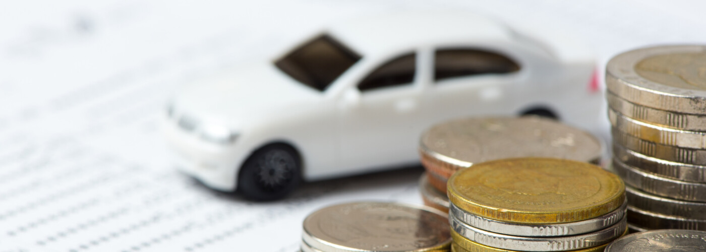 Miniature car with stack of coins on top of paperwork - Car Loan With Bad Credit concept image