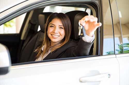 Woman who just purchased a car smiling and showing keys