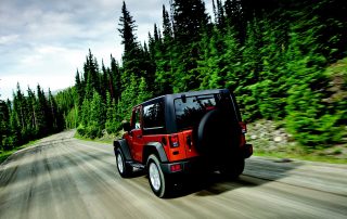 Jeep Wrangler driving through forested road - best jeep wrangler accessories concept