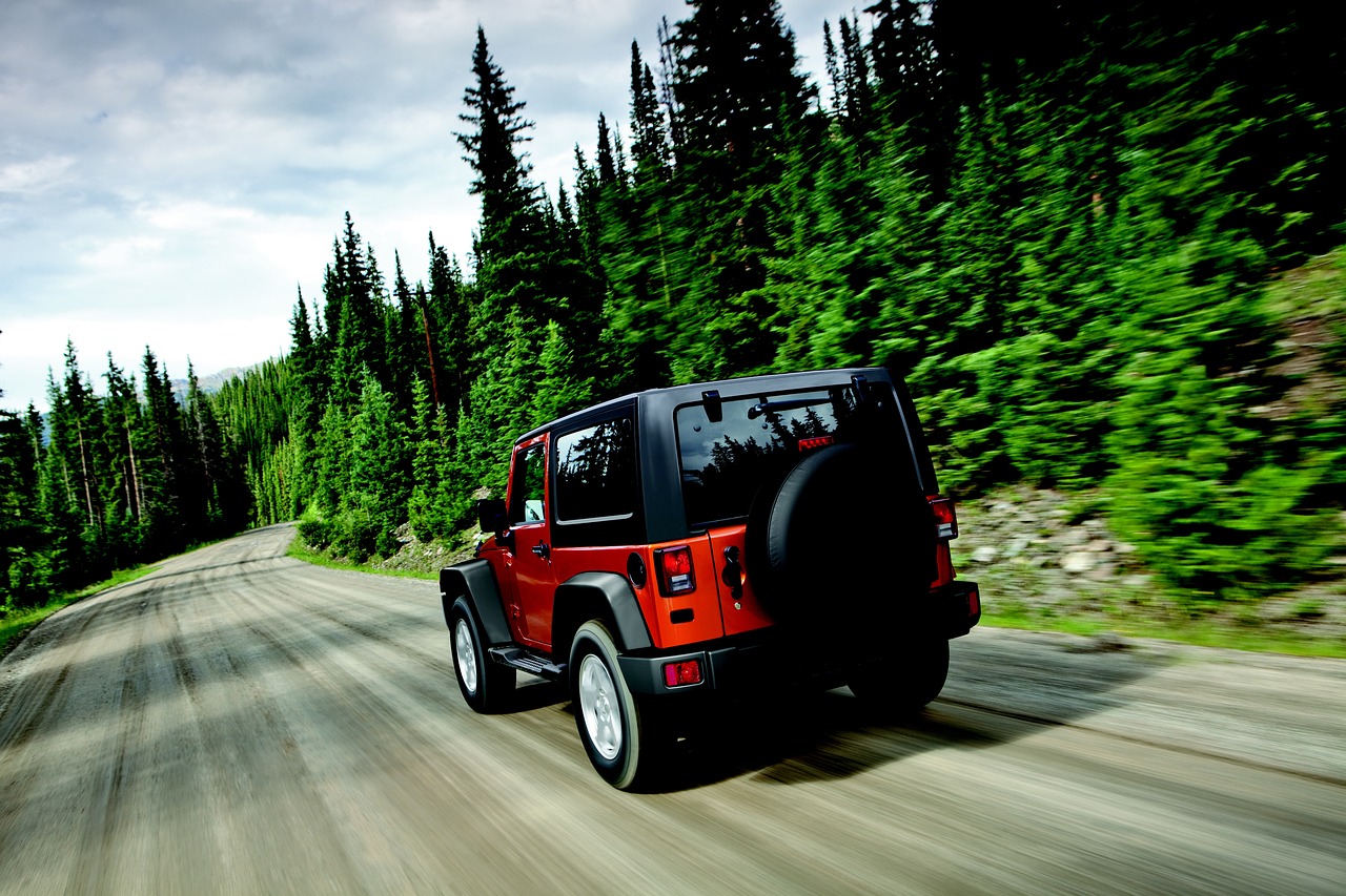 Jeep Wrangler driving through forested road - best jeep wrangler accessories concept